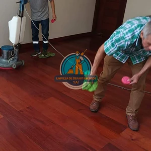 Operarios limpiando el piso de madera de una cocina con máquina pulidora