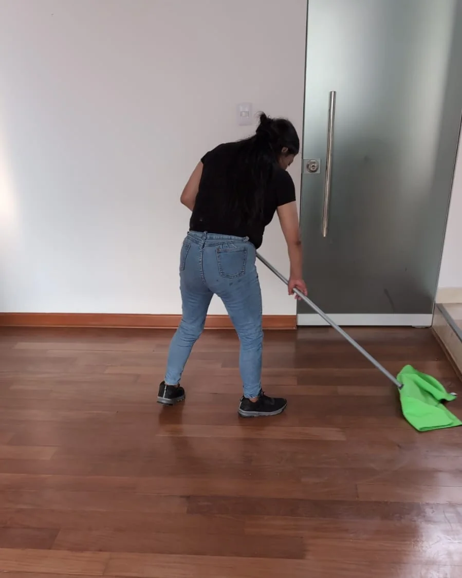 Operaria trapeando el piso de madera de un departamento en Lima