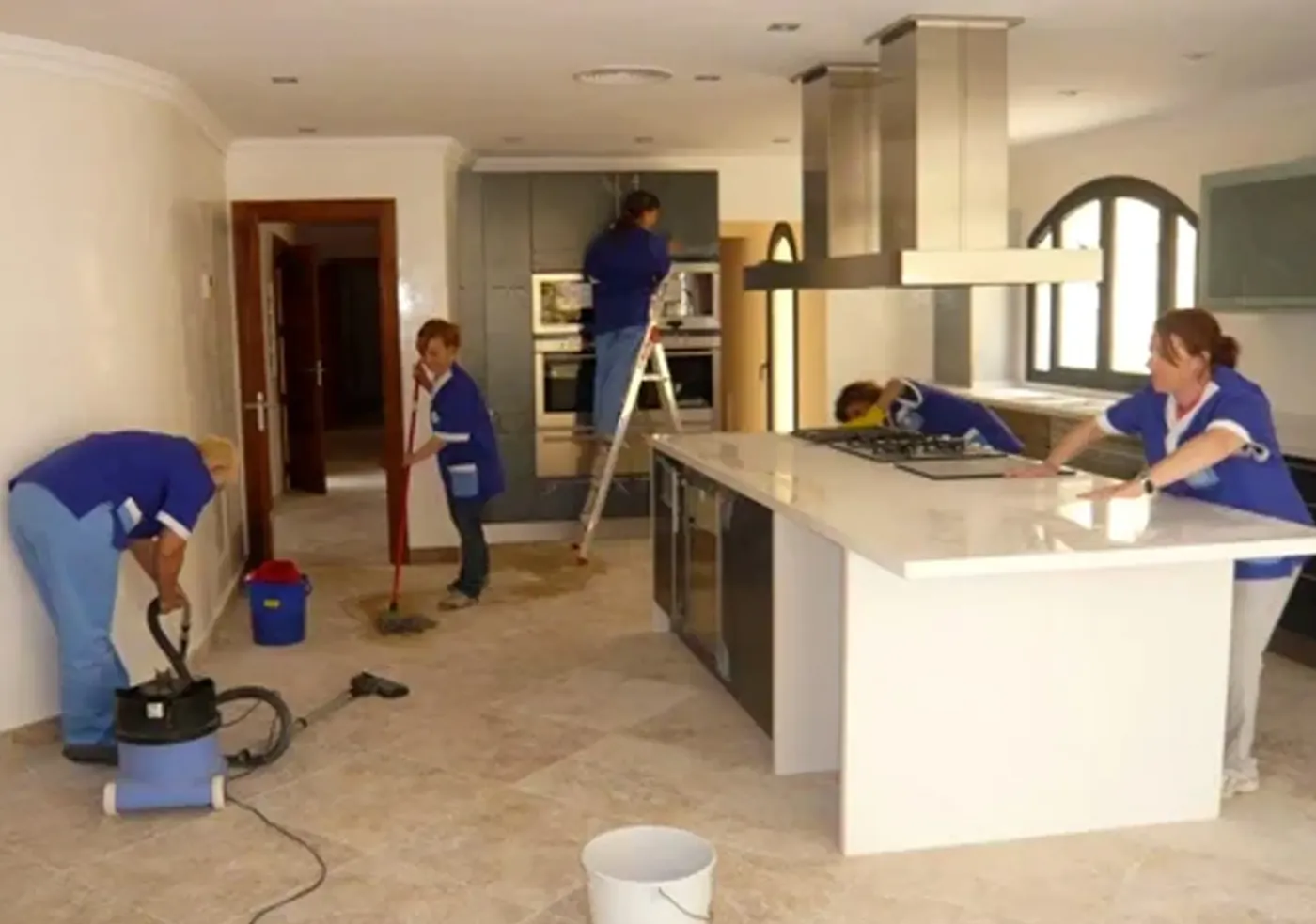 Equipo de limpieza trabajando en la cocina y sala de un departamento recién construido