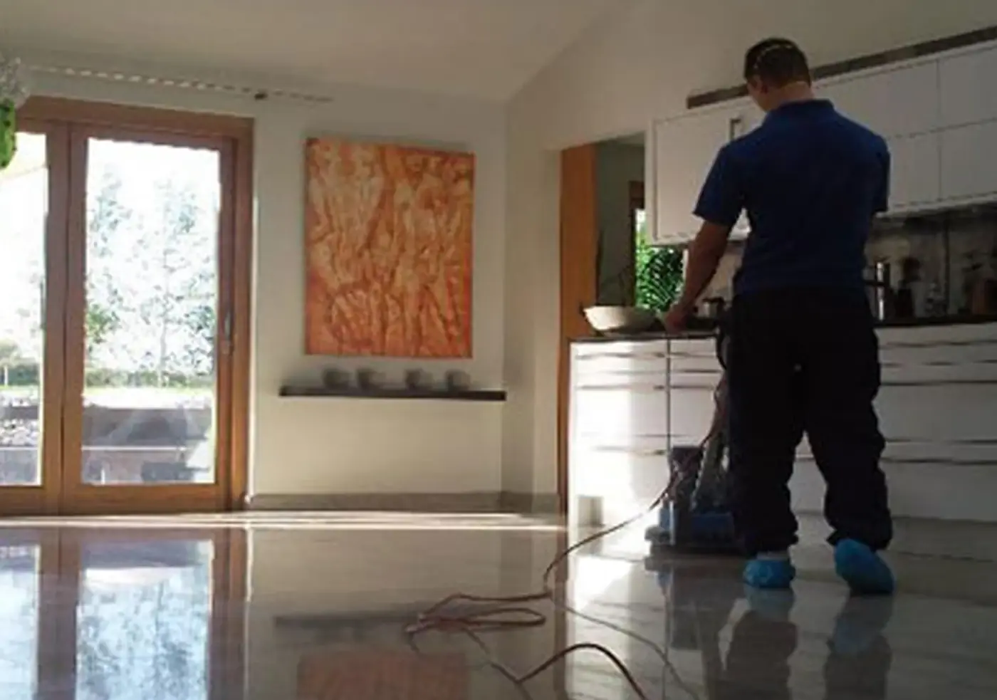 Operario lavando el piso de mármol de una sala con máquina tras el final de obra