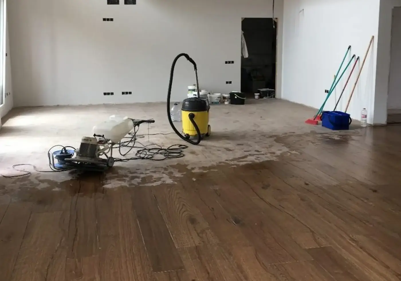 Máquina pulidora limpiando un piso de madera en un departamento recién entregado